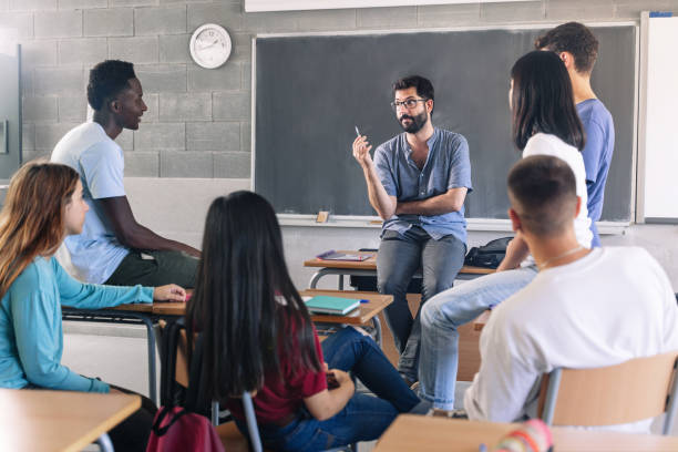 teenager students and young male teacher sharing group discussion at school